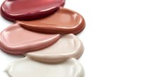 Cosmetic foundation and concealer smears in various nude shades on white background. Makeup base samples showing different skin tones for beauty routine.