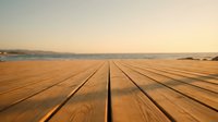 Wooden deck planks extending toward ocean horizon at sunset with warm golden light creating peaceful coastal atmosphere for relaxation and vacation concepts.