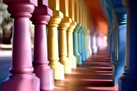 Colorful architectural columns in rainbow sequence creating vibrant perspective with dramatic shadows on wooden floor.
