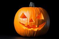Glowing carved Halloween pumpkin with classic jack o'lantern face featuring triangular eyes and jagged smile on black background, illuminated from within.