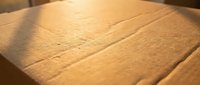 Close-up of natural wood grain texture with warm lighting showing detailed surface patterns and organic lines for carpentry and construction projects.