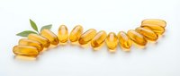 Omega-3 fish oil capsules arranged in a curved line with fresh green leaves on white background for health and wellness supplements.