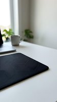 Modern black geometric mouse pad on white desk with laptop and coffee cup in minimalist home office workspace for productivity and remote work setup.