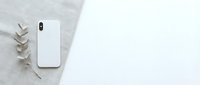 White smartphone with blank screen and eucalyptus branch on neutral textured background. Minimalist flat lay composition for mockup and branding projects.