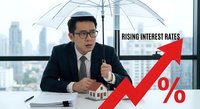 Asian businessman in suit analyzing rising interest rates with red arrow graph in modern office, financial crisis economic growth concept.