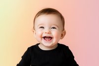 Joyful baby wearing black sweater laughing against colorful gradient background showing pure happiness and genuine emotion in studio setting.