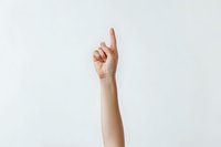 Raised female hand with index finger pointing upward against white background, demonstrating attention, question or leadership gesture.
