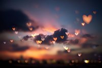 Romantic sunset sky with floating heart bokeh lights creating dreamy atmosphere for Valentine's Day, wedding, love themes and relationship concepts.