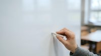 Hand writing on whiteboard with marker in office or classroom setting for business presentation, training, or educational content.