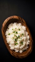 Cooked white rice with fresh herbs served in rustic wooden bowl on dark background for culinary and food photography projects.