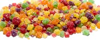 Colorful gummy candies in assorted fruit flavors including red, yellow, green, and orange varieties scattered on white background for confectionery and snack designs.