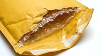 Freshly baked eclair with chocolate filling inside yellow paper wrapper, isolated on white background for bakery, pastry shop, and food packaging design projects.