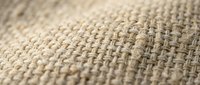 Close-up macro view of natural beige burlap fabric texture showing detailed woven fibers and threads for textile backgrounds and rustic design projects.
