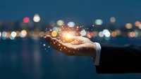 Hand holding glowing light with bokeh city lights at night representing innovation, technology and business solutions for digital transformation.