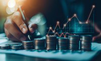 Stacks of coins with rising trend graph overlay showing financial growth and investment success. Hand arranging money while monitoring market performance data.