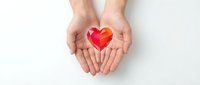Hands gently holding red heart symbol on white background representing love, care, charity, healthcare, donation and compassion for wellness campaigns.