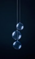 Transparent glass baubles hanging in row against dark background create minimalist holiday decoration with elegant reflections and subtle lighting effects.