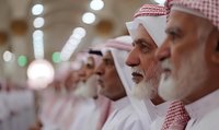 Middle Eastern men in traditional white and red keffiyeh headdress gathered in prayer at mosque, showing spiritual devotion and cultural tradition during worship service.