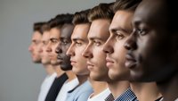 Diverse group of professional men in business attire standing in profile line formation representing teamwork, leadership and corporate unity in workplace.