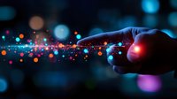 Glowing magical trail of colorful light particles following finger touch against dark background with bokeh effect, creating mystical digital connection effect.