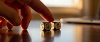 Hand placing wooden dice with cryptocurrency symbols including Bitcoin on table in warm golden light for investment and digital finance concepts.
