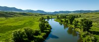 Scenic river flowing through lush green valley with mountains in background, aerial view of natural landscape for environmental and travel content.