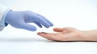 Healthcare professional in blue medical gloves reaching toward patient's open palm, representing trust, care and medical assistance in clinical setting.