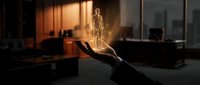 Glowing golden holographic human figure floating above open palm in modern office space with warm lighting and city skyline view through windows.