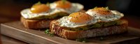 Sunny side up eggs on avocado toast garnished with fresh herbs and spices served on rustic wooden board, breakfast composition in warm lighting.
