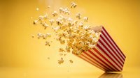 Flying popcorn spilling from red striped container on yellow background for entertainment and snack advertising concepts.