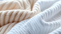 Soft knitted fabric texture in beige and white colors with gentle folds and ribbed pattern creates cozy, warm feeling. For fashion, interior design backgrounds.