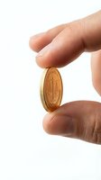 Hand holding golden coin with scales of justice symbol isolated on white background for financial and legal concepts.