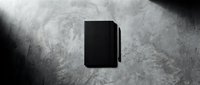 Black book or notebook on grunge concrete surface with dramatic lighting, suitable for publishing, education, and stationery design projects.