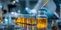 Laboratory scientist using pipette to transfer golden liquid sample into glass vial for chemical analysis and research testing in modern lab facility.