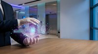 Businessman in dark suit holding glowing holographic brain with digital particles, representing artificial intelligence, innovation, and technology in modern office environment.
