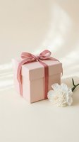 Pink gift box with satin ribbon bow and white carnation flower on neutral beige background for special occasions and celebrations.