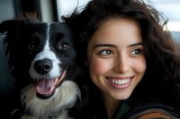 Happy young woman with curly brown hair taking selfie with adorable black and white border collie dog. Pet ownership lifestyle and companionship concept.
