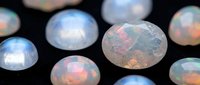 Collection of iridescent opal gemstones displaying rainbow fire colors on dark background for jewelry design and luxury accessories.