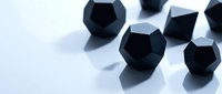 Black matte geometric dodecahedron shapes arranged on a reflective white surface with soft blue shadows, creating a modern minimalist composition.