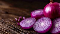 Fresh red onion slices arranged on rustic wooden surface showing vibrant purple rings and layers in natural lighting, macro food photography.
