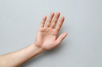 Caucasian person showing open palm gesture against light background, demonstrating nonverbal communication and body language in professional setting.