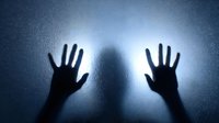 Silhouette of hands pressed against frosted glass with mysterious shadowy figure behind, creating eerie atmospheric mood for thriller or horror concept.