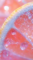 Macro shot of fresh grapefruit slice with water droplets and bokeh effect in pink and coral tones, creating dreamy abstract background for wellness and freshness concepts.