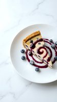 Gourmet cheesecake slice with blueberry sauce swirl and fresh berries on white plate, elegant restaurant dessert presentation on marble surface.