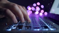 Hands typing on a glowing laptop keyboard with purple bokeh lights in the dark background, evoking technology and digital innovation.