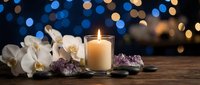 Spa wellness scene with burning candle, white orchid flowers and amethyst crystals on wooden surface against bokeh lights background for relaxation.