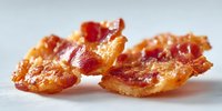 Crispy golden bacon strips with perfect caramelized edges on clean white background, isolated for cooking and breakfast design projects.