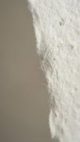 Close-up macro shot of white natural fiber texture with soft fuzzy surface and organic cotton-like appearance for textile and fabric design projects.