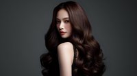 Young Asian woman with luxurious dark brown wavy hair and red lips against dark background. Professional beauty portrait showcasing healthy, shiny hairstyle and glamorous makeup.