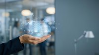 Business professional displaying holographic data analytics and digital charts above open palm in modern office environment for technology presentations.